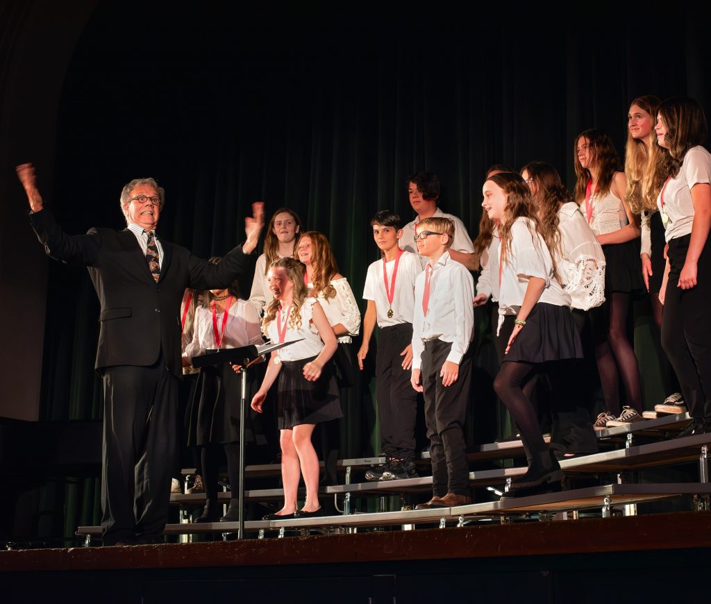 Honor Choir students singing on risers with conductor Rod Harris.