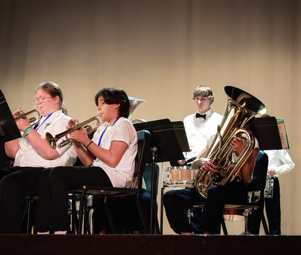 Students playing trumpets and a tuba in the Honor Band.